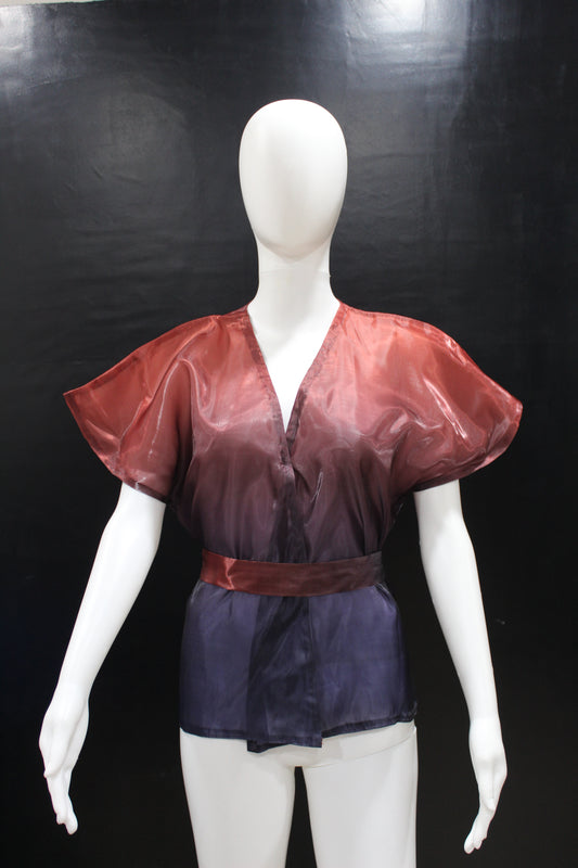 A mannequin displaying a Glass Ombre Red Purple Top with short puffed sleeves and a V-neckline on a dark background.