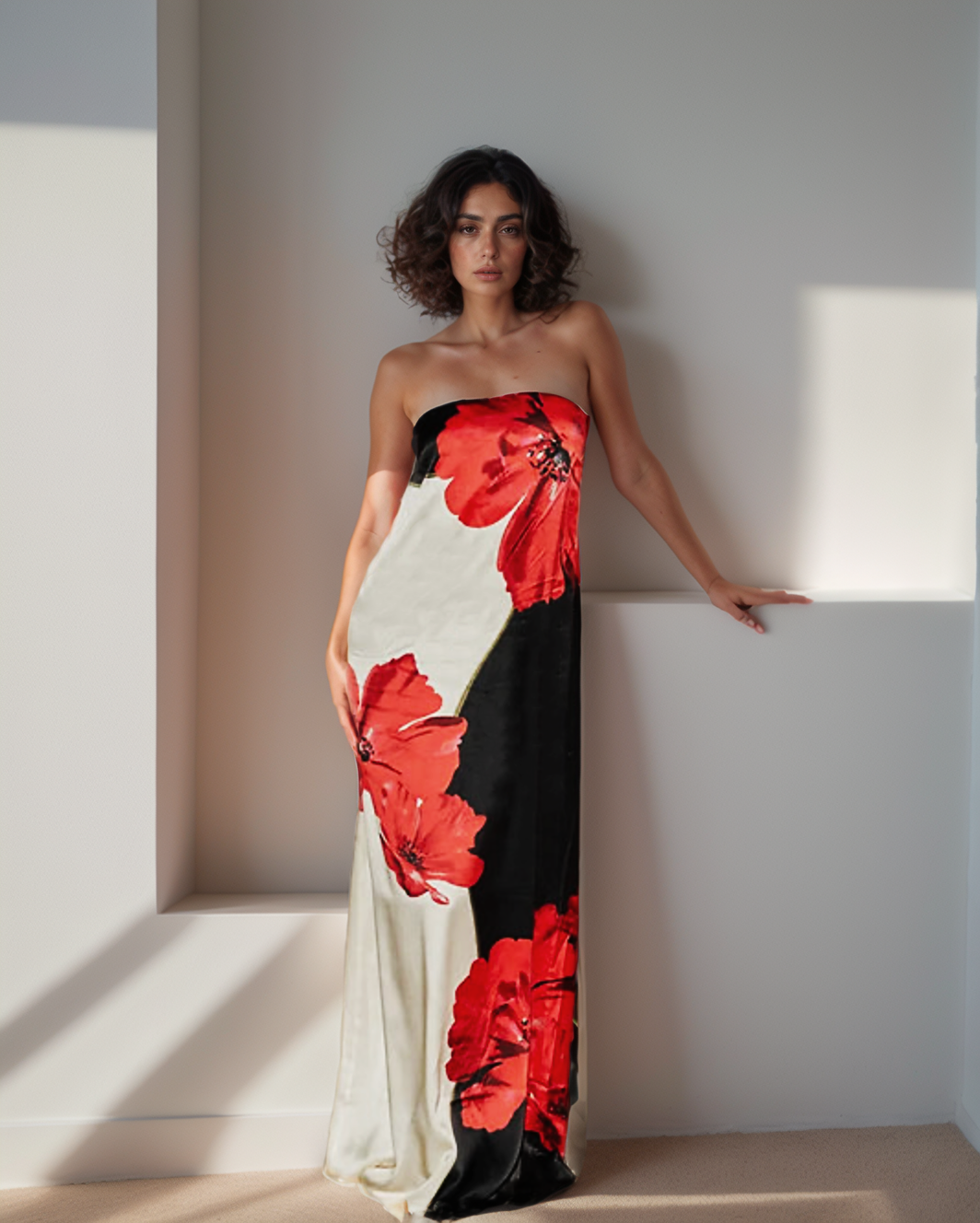 Woman wearing a strapless dress with red floral patterns in a minimalistic setting