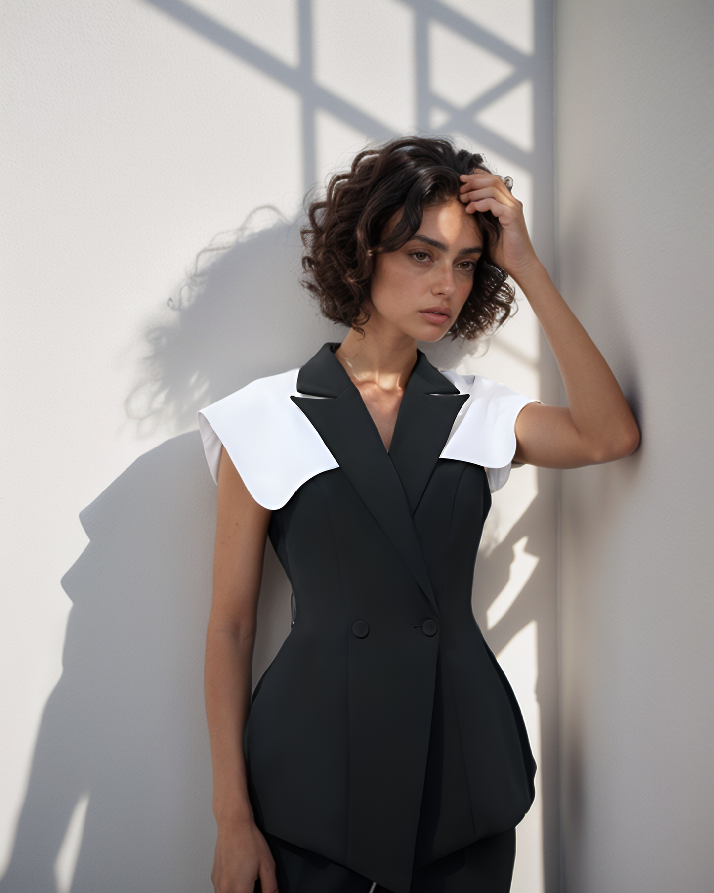 Woman wearing a black outfit with white collar against a light background