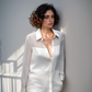 A woman wearing a white sheer shirt with long sleeves, featuring a collar and button-up front.