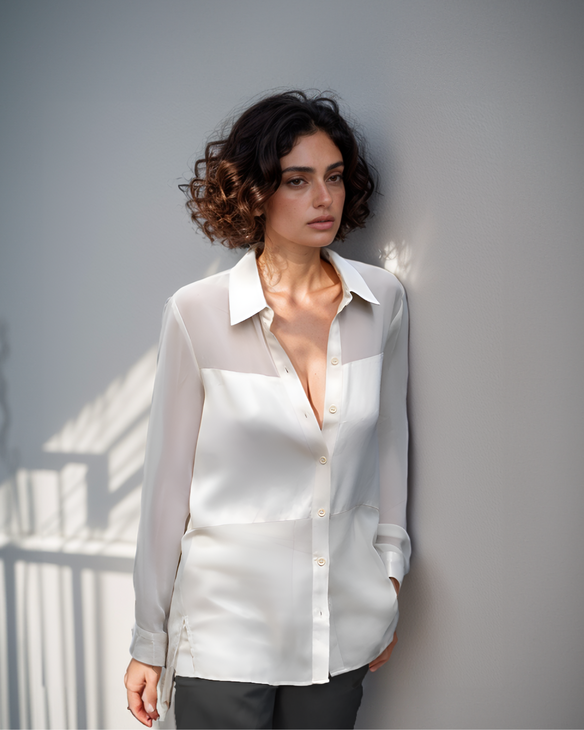 A woman wearing a white sheer shirt with long sleeves, featuring a collar and button-up front.