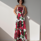 Woman wearing a strapless dress with red rose pattern against a plain background