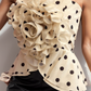 Beige strapless top with black polka dots and ruffled details on a plain background