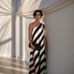 Woman in a black and white striped dress standing in a room with draped curtains.
