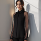 Woman wearing a black sheer blouse over a black shirt with a plain background