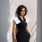 Woman wearing a black and white outfit against a light wall.