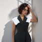 Woman wearing a black outfit with white collar against a light background