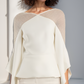 Woman wearing a stylish outfit with a beige top and white pants against a neutral background