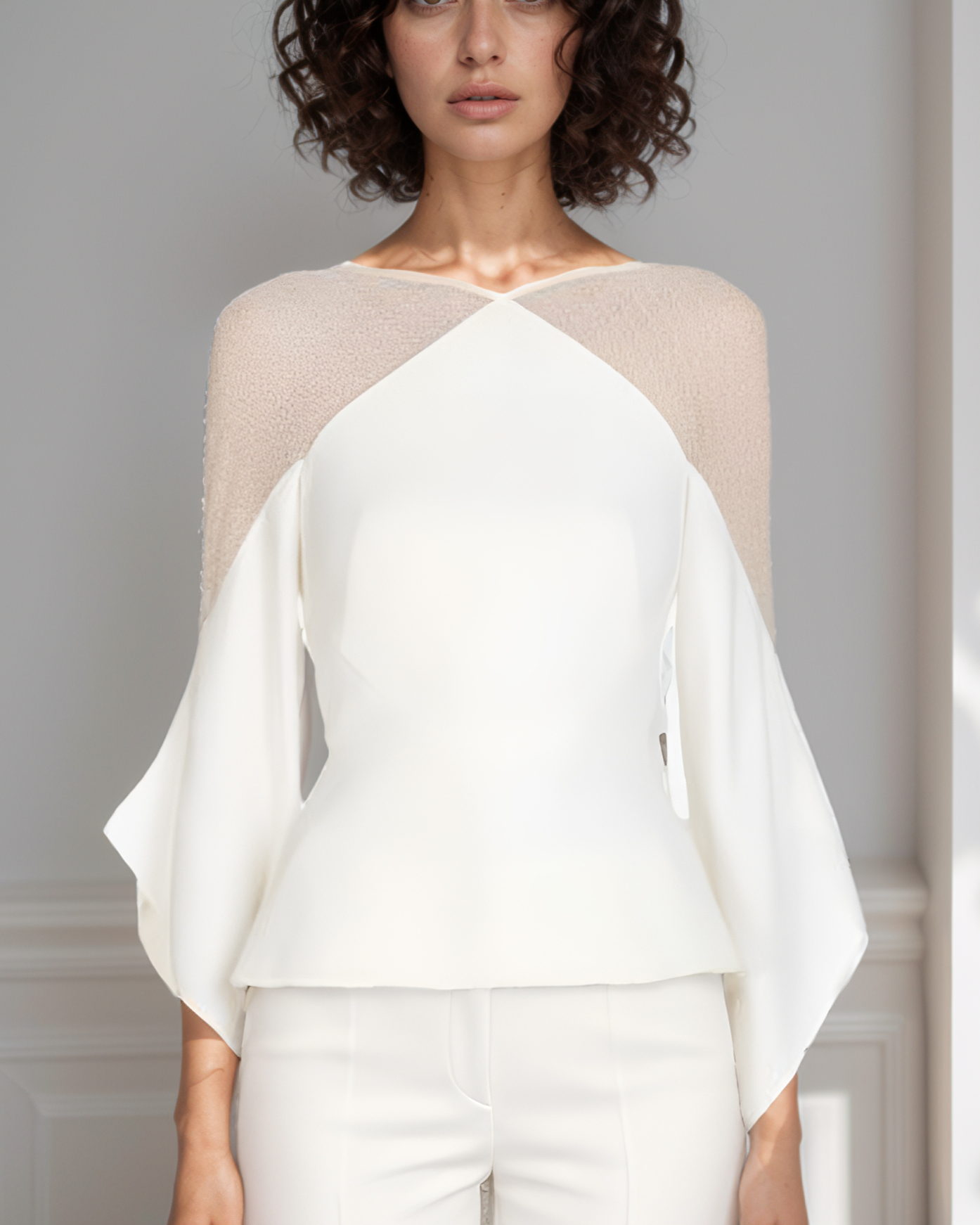 Woman wearing a white and beige top against a plain background