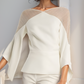 Woman wearing a cream-colored outfit with a light beige cardigan against a neutral background