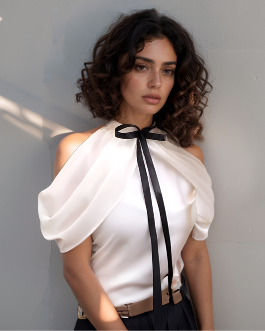 Woman wearing a white blouse with a black ribbon against a gray background