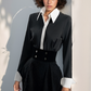Woman wearing a black dress with a white collar against a light gray background