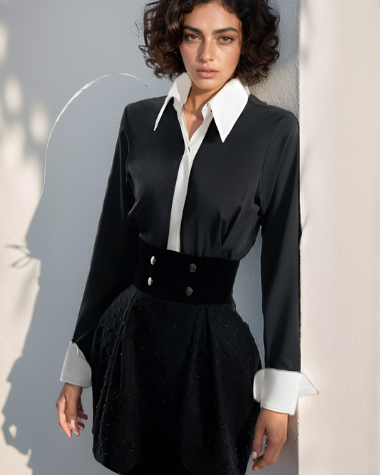 Woman wearing a black dress with a white collar against a light gray background