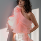 Woman wearing a pink ruffled top with a blurred background
