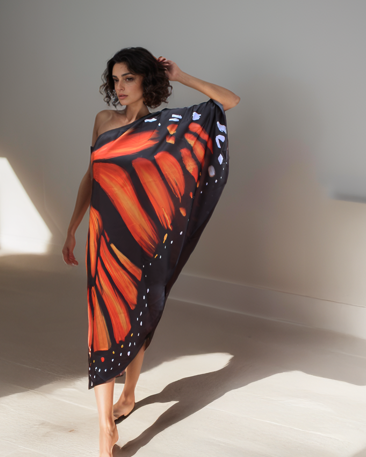 Woman wearing a butterfly-patterned dress against a neutral background