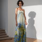 Woman wearing a strapless dress with a gradient design standing against a white wall.