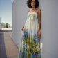 Woman wearing a strapless floral dress against a white wall.