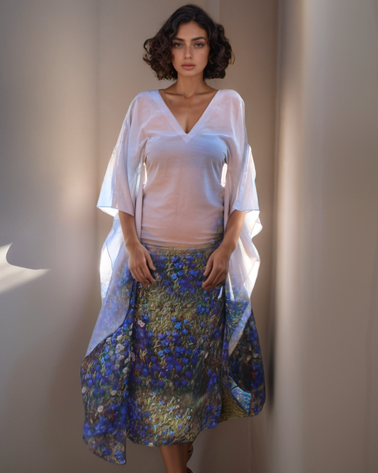 Woman wearing a white top and floral skirt against a neutral wall