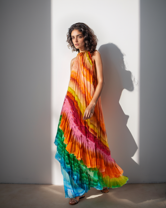 Woman wearing a colorful tie-dye dress against a white wall