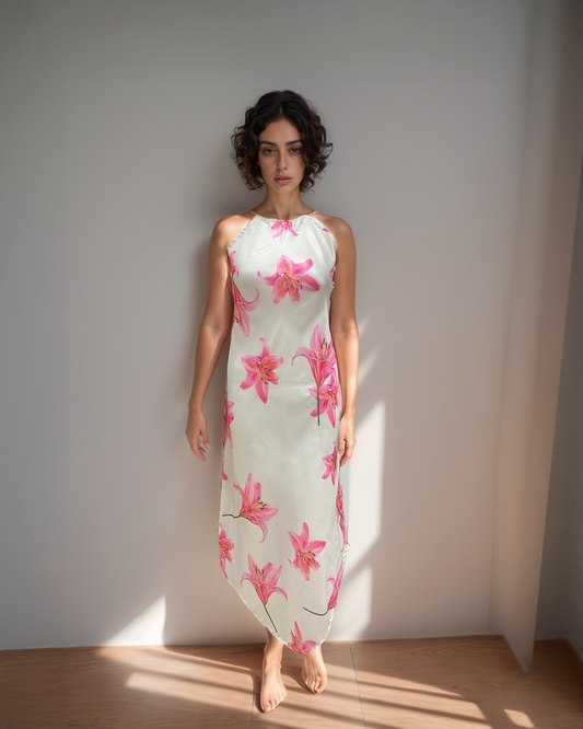 Woman wearing a floral dress standing against a plain wall with sunlight casting shadows.