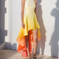 Woman wearing a colorful dress standing against a white wall with shadows.