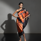 Woman wearing a one-shoulder dress with orange and black pattern on a gray background